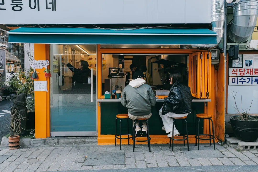 자영업자가 카페 카운터에서 영수증과 노트북으로 매출·경비 정리하는 모습